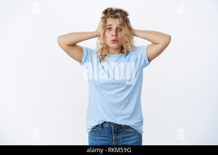 Portrait of panicking troubled woman breathing heavily holding hands on head in despair and concern folding lips and frowning looking insecure and Stock Photo