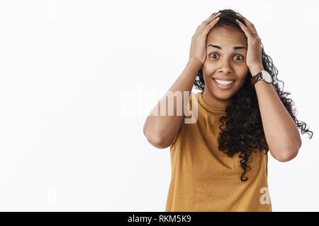 Waist-up shot of surprised happy woman reacting to unbelievable luck grabbing head with hands and smiling broadly being thrilled and excited as Stock Photo