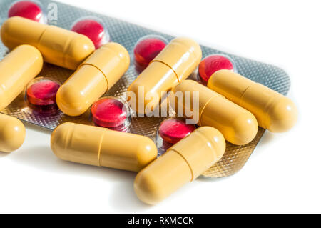 Red and yellow tablets and blisters scattered on a white background Stock Photo