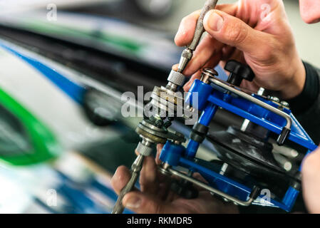 man using repairing equipment to fix damaged cracked windshield. Stock Photo