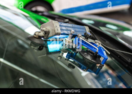 man using repairing equipment to fix damaged cracked windshield. Stock Photo
