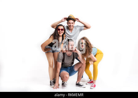 Portrait of joyful young friends with hat and sunglasses in a studio. Stock Photo