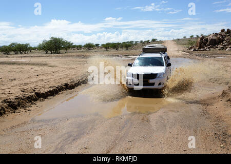 Offroad car 4x4 four wheel. Off-road vehicle splashing up water to sides while crossing a river running through a desert canyon, Namibia Stock Photo
