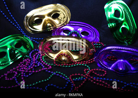 Purple, Green and Gold Mardi Gras masks with beads on a black background Stock Photo