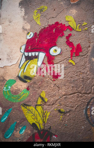 Lisbon, Portugal - 01/03/19: Red Monster Graffiti in downtown Bairro Alto, multiple eyes, yellow tongue and vampire teeth. Paint falling, dried up wal Stock Photo