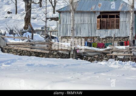 A boy seen holding a jug of water as he walks through a snow covered field during a sunny winter day on the outskirts of Srinagar, Indian administered Kashmir. Weather in the Kashmir valley has shown improvement after the heaviest snowfall. The main National Highway that connects the valley with the rest of the country remained closed for the sixth consecutive day following an avalanche killing seven people including the three policemen, the two firefighters and the two prisoners. The weather man has forecast heavy rain and snowfall from Feb 13. Stock Photo