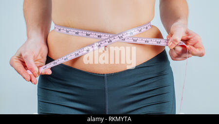 Overweight woman with tape measure around waist. Woman measuring her waistline fat tummy Stock Photo