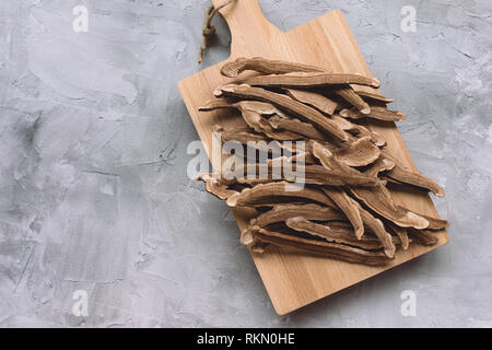 Slices of dried lingzhi mushroom, also called reishi or Ganoderma Lucidum, on a wooden board, gray background. Chinese traditional medicine product. Stock Photo