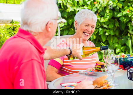 A mature couple enjoying a meal outside on their patio with a glass of wine.  Model Releases 20070822 MR C 20070822 MR D 20070822 PR A Stock Photo