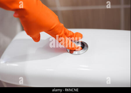 woman's finger pushing button and flushing toilet. Stock Photo