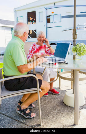 A mature couple using laptop computers outside their trailer on their patio while one talks on the phone.  Model Releases 20070822 MR C 20070822 MR D  Stock Photo