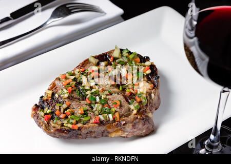 https://l450v.alamy.com/450v/rkndfn/grilled-steak-served-on-a-white-plate-with-finely-chopped-vegetables-and-a-glass-of-red-wine-rkndfn.jpg