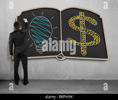 businessman drawing lamp and money symbol on book shape blackboard Stock Photo