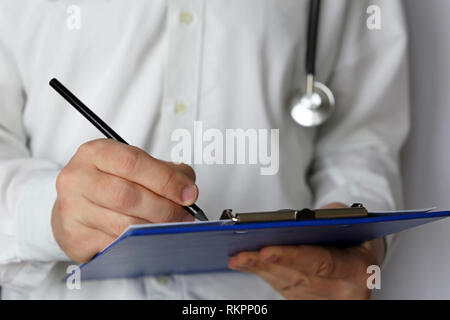 Medical exam, doctor with stethoscope writes a prescription paper. Concept of medicine, diagnosis, filling up an history form and recommend treatment Stock Photo