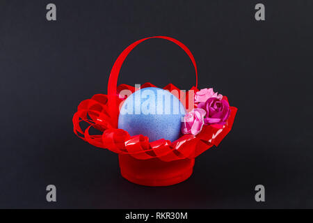 Diy Easter egg basket made of red plastic cup decorated with artificial flowers black background. Gift idea, decor Spring, Easter. Process kid childre Stock Photo
