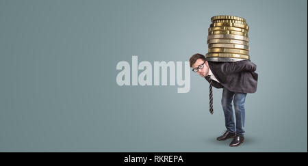 Businessman carrying a giant stack of coins on his back Stock Photo