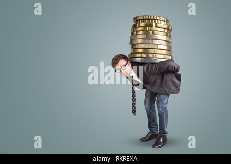 Businessman carrying a giant stack of coins on his back Stock Photo
