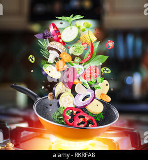 Flying fresh vegetables and spices falling into a pan. Flying motion effect.Gas-stove at the background. Stock Photo