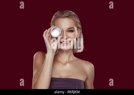 Young model smiling while promoting her favorite cream Stock Photo