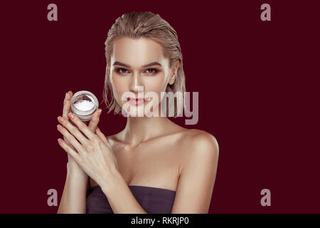 Slim appealing professional model holding little pack of cream Stock Photo
