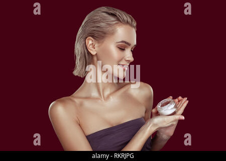 Slim model with natural makeup promoting cream while posing Stock Photo