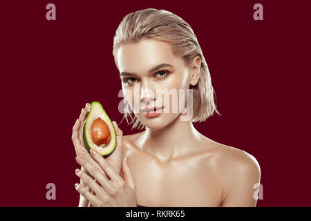 Young appealing photo model posing with avocado in her hand Stock Photo