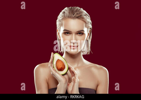 Model with bob cut having nice makeup while posing with avocado Stock Photo