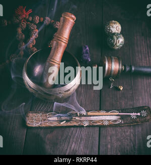 copper singing bowl and a wooden stick on a brown table Stock Photo