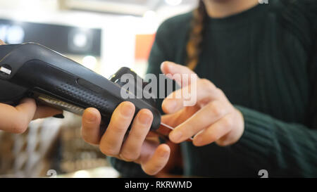 girl pays with a card in the terminal and enters a pin code. Stock Photo