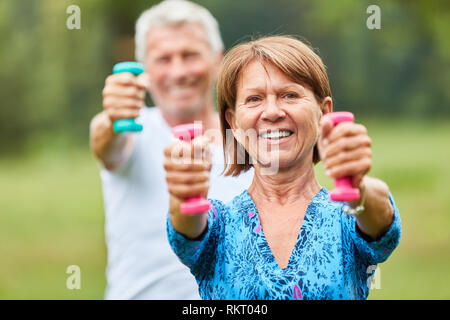 Senior couple exercising with dumbbells in a rehabilitation course for toning Stock Photo