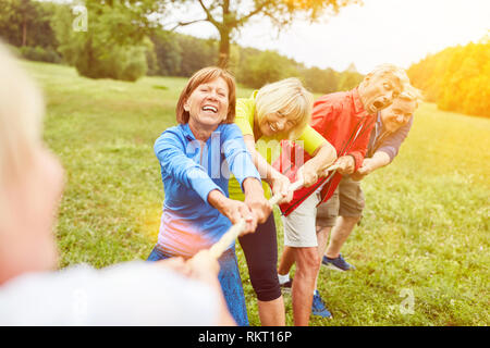 Group of seniors in tug of war or rope pulling competition in nature Stock Photo