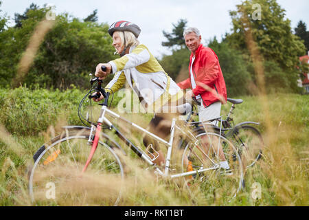 Active senior couple riding a bicycle on a nature bike ride Stock Photo