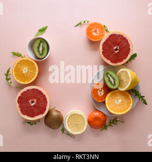 Tropical fruits frame from orange, lemon, tangerine and kiwi on pink paper background. Healthy food concept. flat lay. Top view Stock Photo