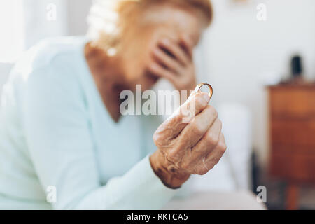 Heartbroken elderly woman holding he husbands wedding ring Stock Photo