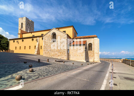 Antibes Cathedral on small town square and road along Mediterranean sea under beautiful blue sky in France. Stock Photo