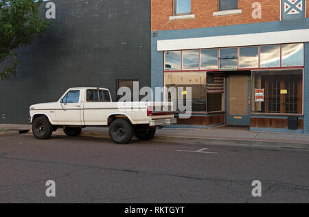 Classic Ford pick-up truck near closed shop in Winslow, Arizona, United States of America. Store with for sale and for rent sign and American flag on  Stock Photo
