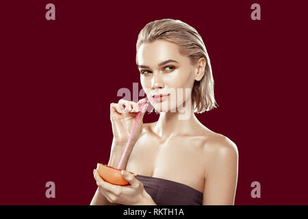 Model with short blonde hair drinking some grapefruit juice Stock Photo