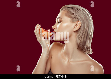 Blonde-haired model posing with juicy grapefruit sideways Stock Photo