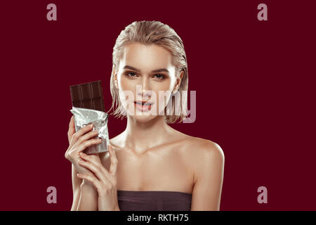 Slim appealing model holding bar of dark chocolate Stock Photo