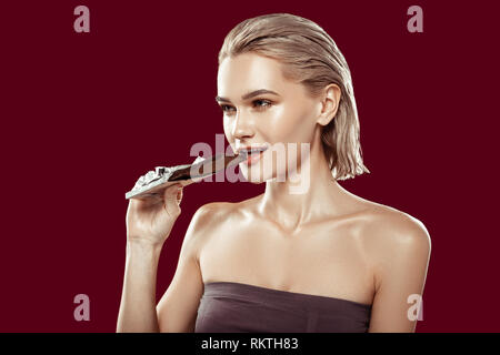 Young model working for food magazine biting piece of chocolate Stock Photo
