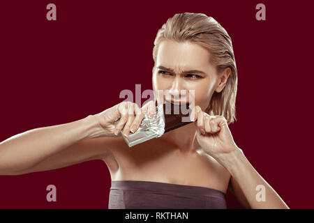 Blonde-haired woman with bob cut biting dark chocolate Stock Photo