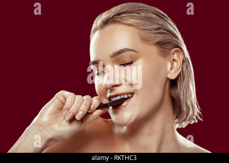 Close up of woman with natural makeup biting chocolate Stock Photo
