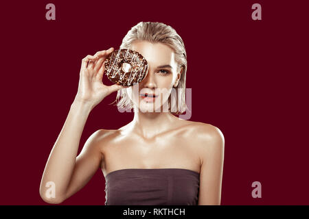 Slim young model posing holding chocolate doughnut near her eye Stock Photo