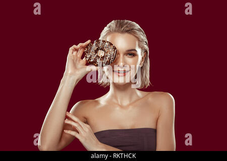 Slim photo model holding chocolate doughnut while posing Stock Photo