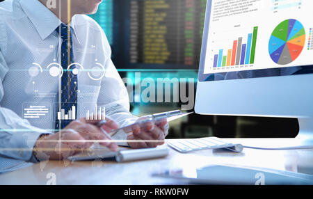 Businessman looking into a modern desktop computer screen reviewing a return on investment or business performance with colourful graphs. Stock Photo
