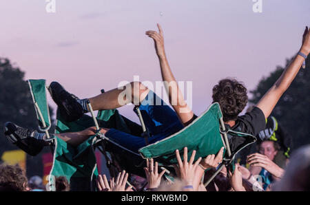 A fan is crowd surfing in his deck chair during Alt J performance at Latitude Festival 2018. Stock Photo
