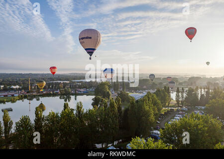 Balloons floating above spectators at the Northampton Balloon Festival at sunrise. Stock Photo