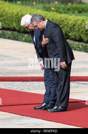 12 February 2019, Colombia, Bogotá: Federal President Frank-Walter Steinmeier (l) is greeted with military honours by Ivan Duque Marquez, President of Colombia, and bowes with him before the national flags. Steinmeier and his wife visit Colombia and Ecuador on the occasion of Alexander von Humboldt's 250th birthday as part of a five-day trip to Latin America. Photo: Bernd von Jutrczenka/dpa Stock Photo