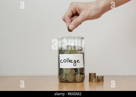 Distribution of cash savings concept. Hand puts coins to the glass money boxes with inscription 'college' Stock Photo