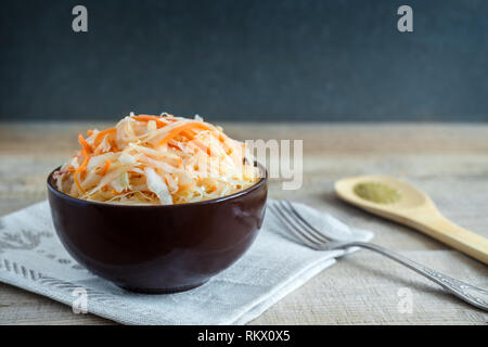 In a ceramic Cup on an old wooden table sauerkraut with carrots. Stock Photo